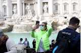 En kvinna med ansiktsmask tar en selfie framför Fontana di Trevi i Rom