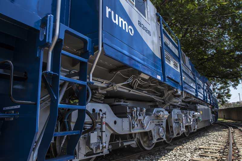Ett mellanblått lok med den brasilianska tågoperatören Rumos logga till vänster i bild.