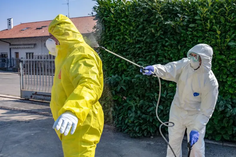 Två personer iklädda heltäckande skyddsutrustning